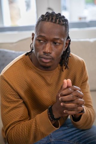 Thoughtful man in casual outfit relaxing on couch indoors