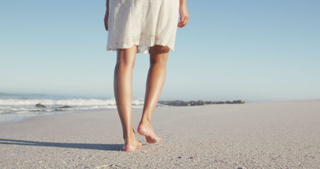 Legs of biracial woman walking on sunny beach with wet sand. Summer, relaxation, vacation, happy time.