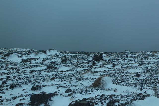 Snow-Covered Rocky Terrain Under Dark Overcast Sky - Download Free Stock Photos Pikwizard.com
