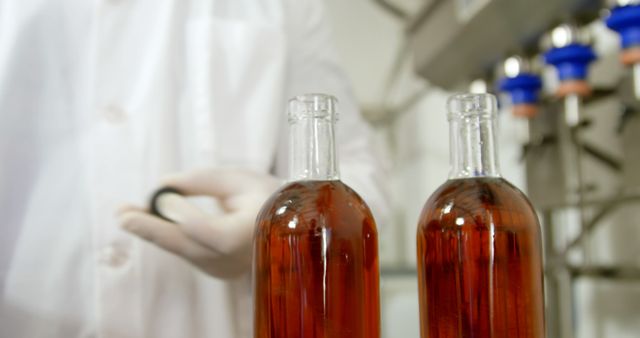 Depicts a quality control inspector in a lab coat examining bottled beverages in a production facility. Can be used in publications related to industrial production, beverage manufacturing, quality assurance practices, and product testing processes.