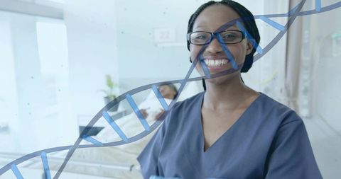 Smiling nurse wearing navy scrubs and glasses standing in hospital room with dna helix
