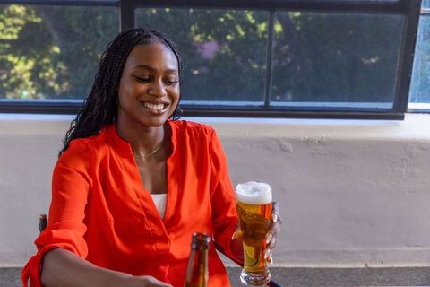 African american woman enjoying drink by bright window