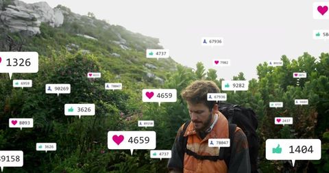 Backpacker receiving social media notifications while hiking green rocky mountain trail