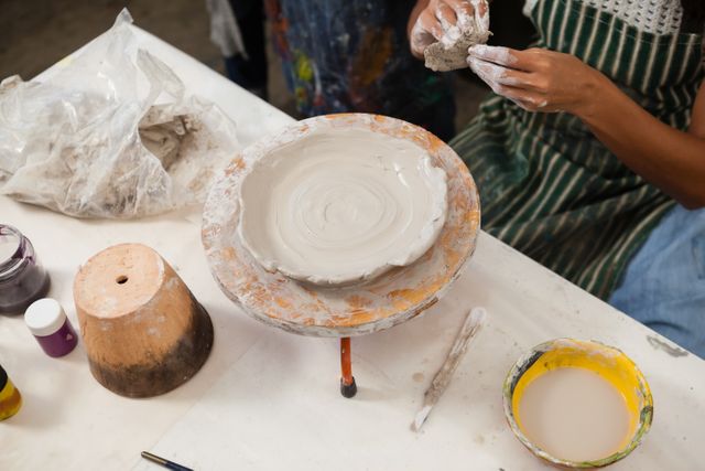 Mid section of woman learning pottery in class