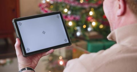 Elderly man using tablet in cozy christmas living room