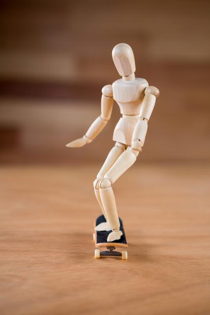 This image depicts a wooden figurine balancing on a skateboard on a wooden floor. It can be used to illustrate concepts of balance, movement, and playfulness. Ideal for creative projects, hobby-related content, or educational materials about physics and motion.