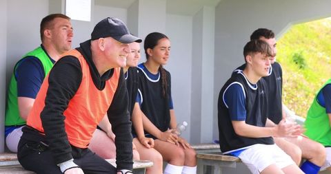 Soccer team on wooden bench in dugout wearing training bibs