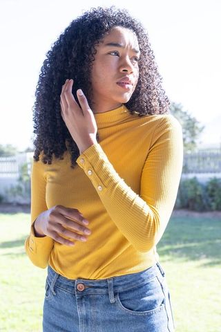 Woman in bright yellow sweater outdoors showing casual style