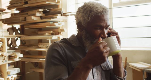 Carpenter Drinking Coffee While Taking a Phone Call in Wood Workshop - Download Free Stock Images Pikwizard.com