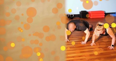 Fitness duo performing push-ups on wooden studio floor with stacked steps and smartwatch