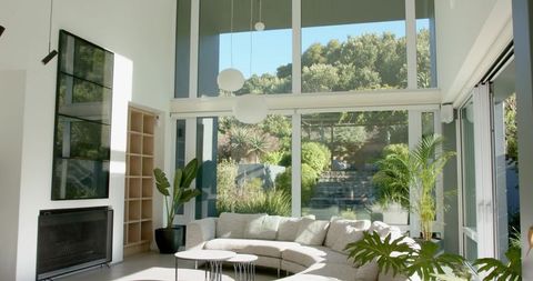 Sunlit modern living room showcasing curved light-gray sectional, floor-to-ceiling glass