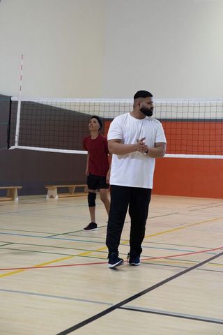 African american coach coaching, clapping and guiding asian teen at indoor volleyball court