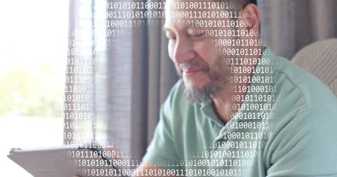 Senior man using tablet at home with binary code overlay, data connectivity and technology