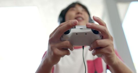 Young gamer engaged in playing with headphones and game controller