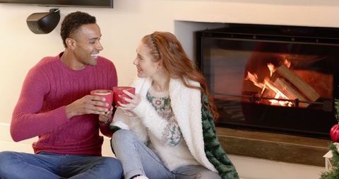Couple Enjoying Hot Drinks by Fireplace in Festive Living Room