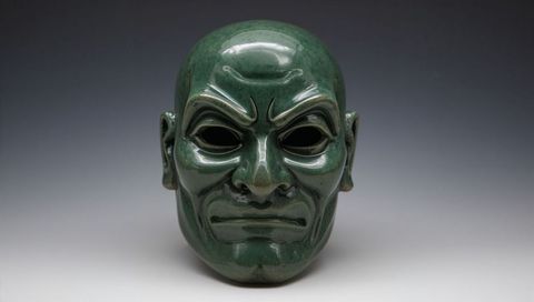 Glossy green ceramic ceremonial mask showing fierce expression and shiny glaze