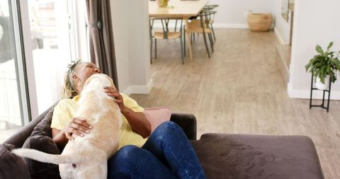 Senior Woman Relaxing on Couch with Her Dog in Cozy Living Room