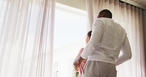 Couple Embracing While Drawing Curtains in Bedroom