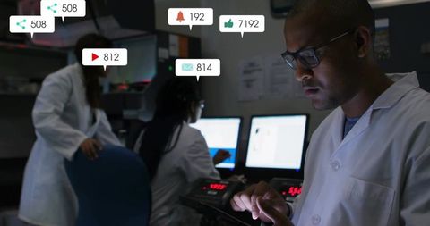 Monitoring scientist using tablet in dim control room with social media notifications