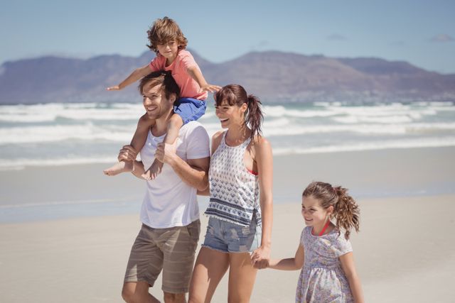 Happy family walking at beach during sunny day