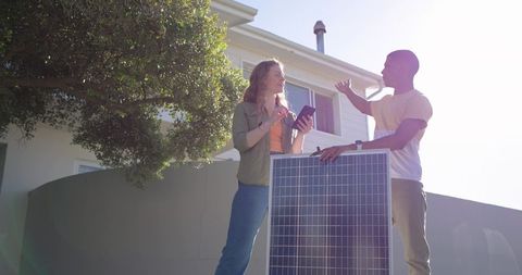 Diverse couple installing residential solar panel, discussing system using tablet