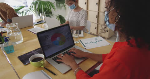 Diverse Team Analyzing Data on Laptops in Modern Office