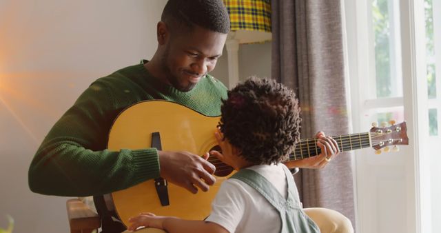 Image of light flashing over happy african american father and son playing guitar. Family, parenthood, music and spending time together concept digitally generated image.