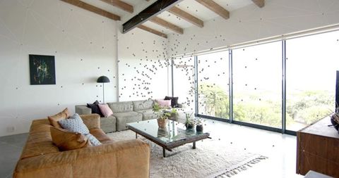 Modern living room featuring tan leather sofa, vaulted beams and floor-to-ceiling windows