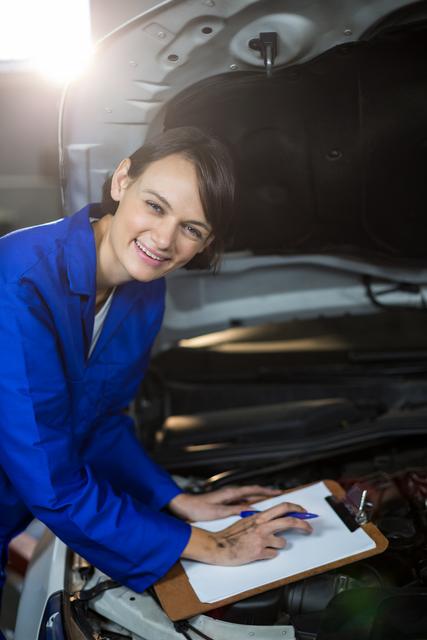 Female mechanic smiling while preparing a check list in repair garage