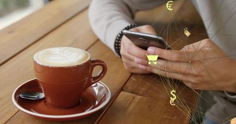 Man using smartphone at cafe with latte and ecommerce icons for mobile shopping
