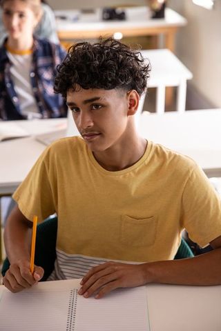 Diverse teenage students studying in high school classroom