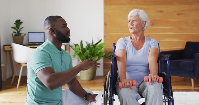 Image of african american male physiotherapist exercising with caucasian senior woman. seniors health and nursing home lifestyle concept.