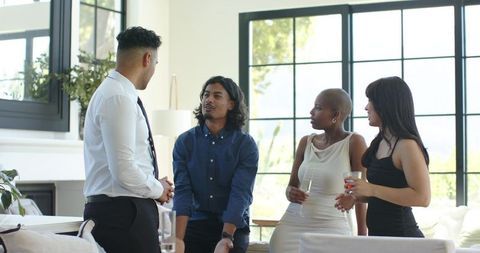 Young professionals networking and chatting in modern living room during daytime gathering