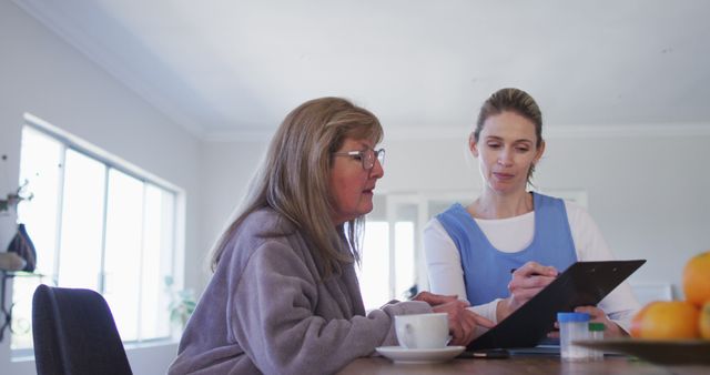 Caregiver Assisting Senior Woman with Paperwork at Home - Download Free Stock Images Pikwizard.com