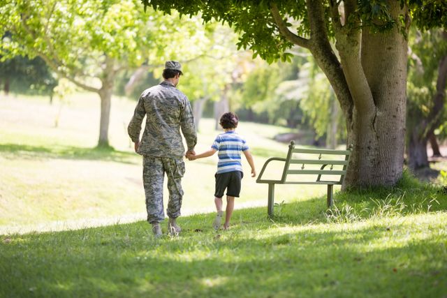 Rear view of army soldier walking boy in park