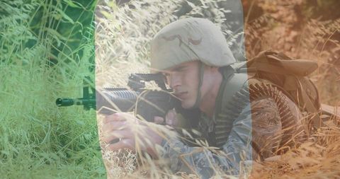 Prone Soldier Aiming Belt-Fed Machine Gun in Tall Grass Wearing Combat Helmet, Camo Uniform