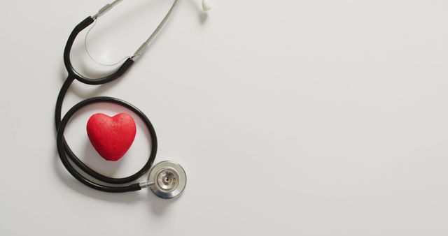 Image depicts stethoscope placed beside a red heart on a white background, symbolizing heart health and medical care. Useful for articles and websites focused on healthcare, cardiology, health and wellness promotion, medical equipment, and doctor's office visuals.