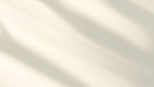 Soft diagonal shadow stripes on ivory surface creating minimal sunlit texture, calm mood