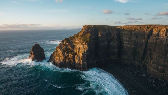 Golden Light Bathing Rugged Coastal Cliffs with Offshore Sea Stack