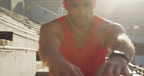 Determined Athlete Stretching in Sunlit Stadium