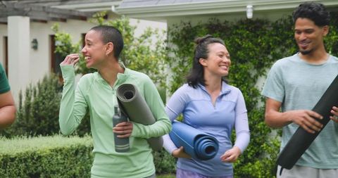Diverse friends gathering outdoors with yoga mats smiling