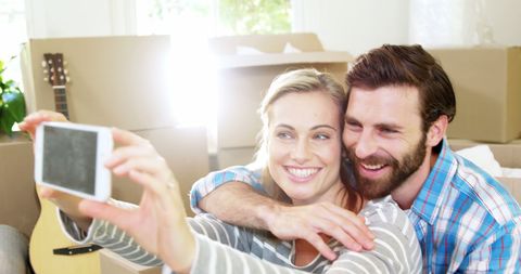 Happy couple taking selfie while moving to new home