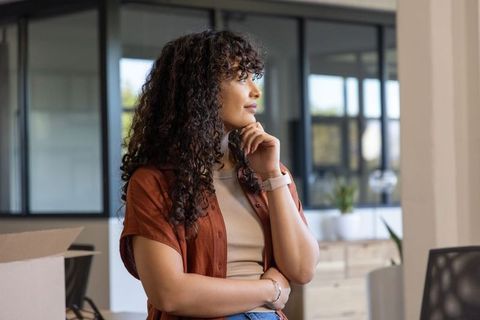 Female professional standing in modern office contemplating during unpacking and move-in