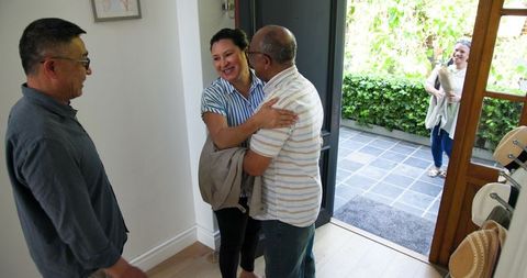 Senior Friends Joyful Reunion with Gifts at Front Door