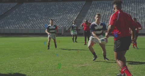 Rugby players passing and receiving ball on stadium pitch with colored training markers