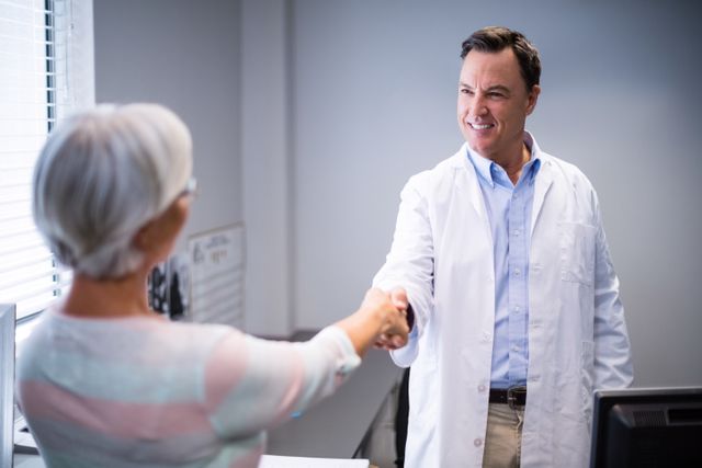 Doctor greeting senior patient with a handshake in a clinic. Ideal for illustrating healthcare services, patient-doctor relationships, medical consultations, and elderly care. Useful for medical websites, healthcare brochures, and patient care articles.