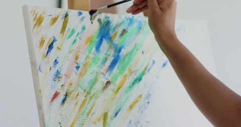 Adult woman painting abstract canvas with fine brush closeup showing colorful texture