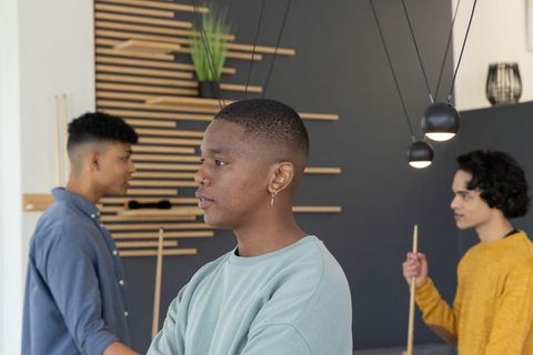 Diverse young men relaxing around pool table in modern lounge under pendant lights