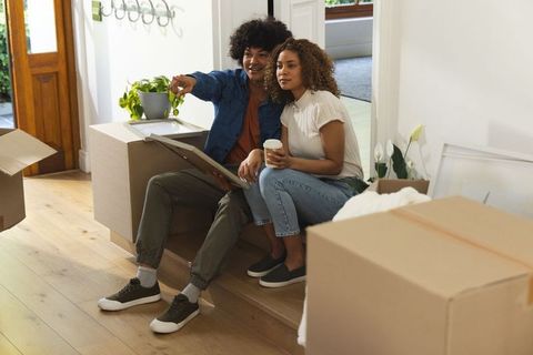 African american couple sitting on entry step surrounded by moving boxes and framed art