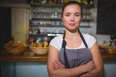 Confident Female Cafe Owner in Striped Apron in Cozy Setting